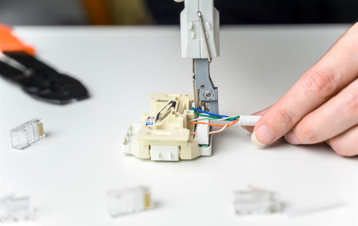 Technician terminating low-voltage cabling at a connection jack